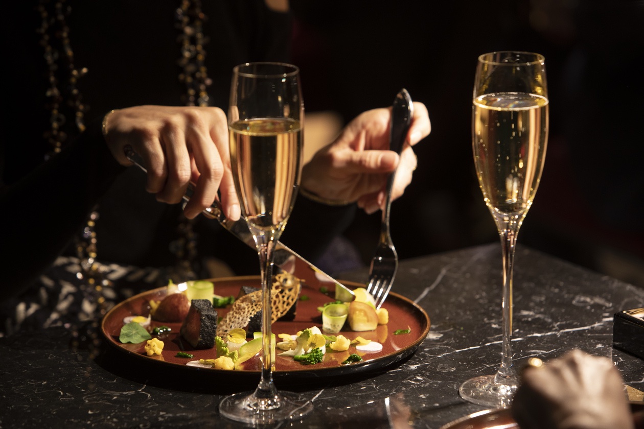 A private table set with champagne and a plated course, in low light